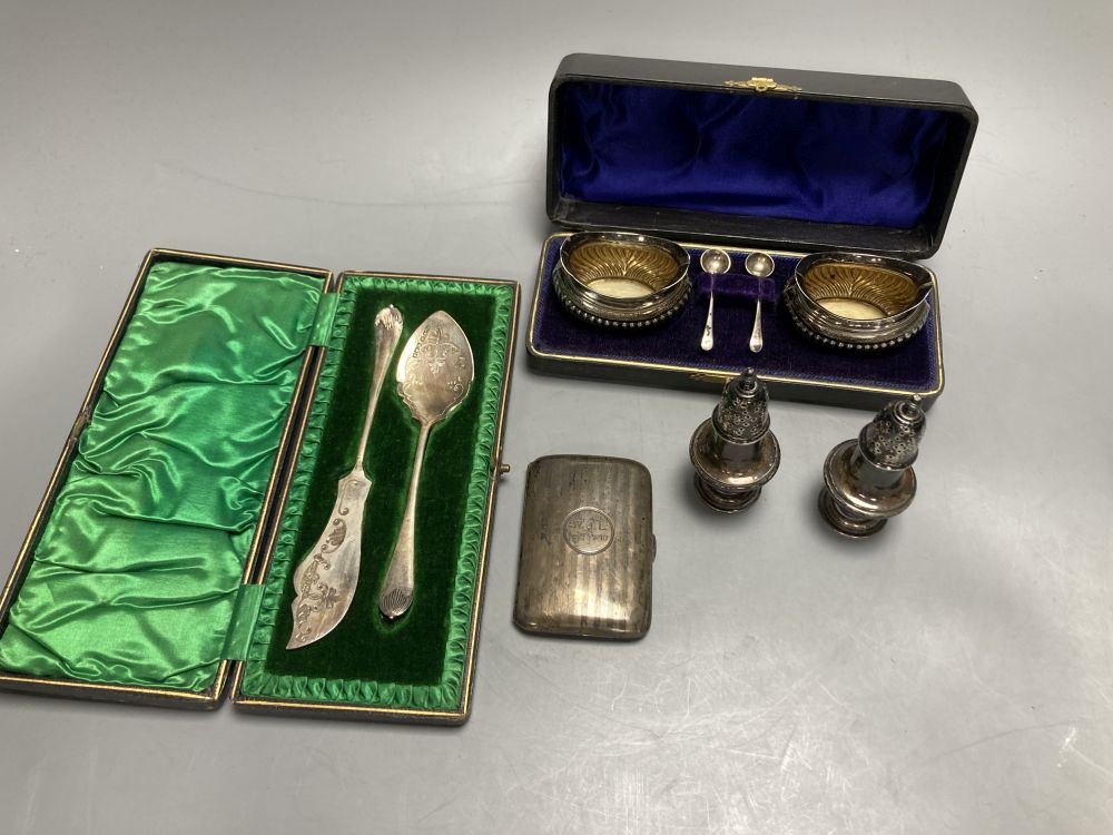A pair of oval silver salts and spoons (cased), a butter knife and preserve spoon (cased), two pepperettes & a silver cigarette case